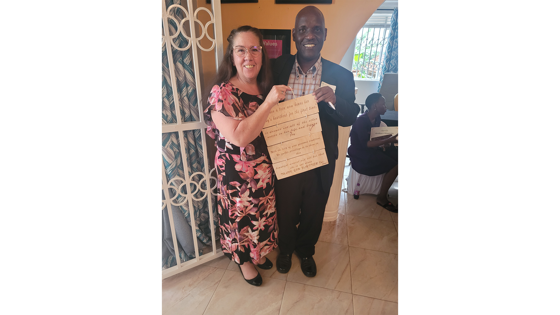 Flutter team member and a pregnancy center partner holding a certificate together